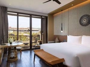 ein Hotelzimmer mit einem großen Bett und einem Balkon in der Unterkunft Pullman Resort Xishuangbanna in Jinghong