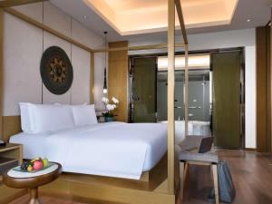 a bedroom with a large white bed and a table at Pullman Resort Xishuangbanna in Jinghong