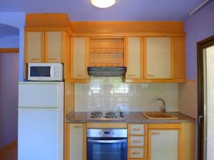 a kitchen with wooden cabinets and a white refrigerator at Rentalmar Diplomatic Park in Salou