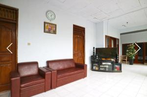 ein Wohnzimmer mit 2 Ledersofas und einem TV in der Unterkunft Ibus room canggu By SDM in Canggu