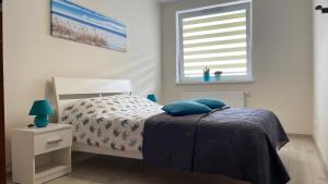 sypialnia z łóżkiem z niebieskimi poduszkami i oknem w obiekcie Apartament Morski Lazurowy Gdynia w mieście Gdynia