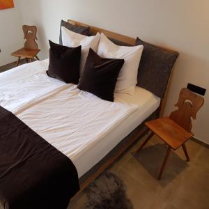 a bed with black and white pillows and a chair at Rooftop-Schenna in Schenna