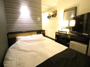 a bedroom with a bed and a desk and a television at APA Hotel Komatsu Grand in Komatsu