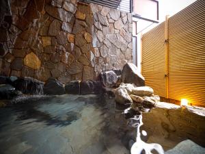 APA Hotel Komatsu Grand في كوماتسو: تجمع مياه بجانب جدار حجري