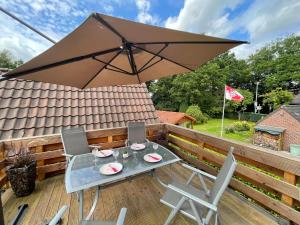 uma mesa e cadeiras num deque com um guarda-sol em Ferienwohnung AmmerSchnucke em Wiefelstede