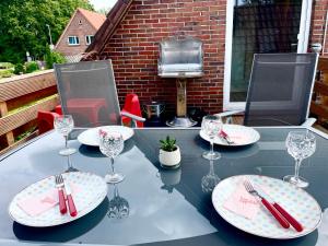 uma mesa com pratos e copos de vinho num pátio em Ferienwohnung AmmerSchnucke em Wiefelstede