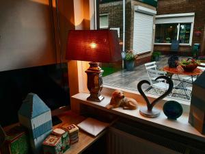 una lámpara sentada en un estante junto a una ventana en Tuinhuis Duinroos Deluxe, en Callantsoog