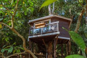 a tree house with a balcony in the trees at Nirvana Hill Resort in Curtorim