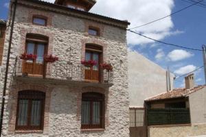 un edificio con ventanas y balcones con flores. en Casa Rural San Roque, en Fuenterrebollo