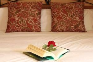 Un libro con una rosa en una cama en Casa Rural San Roque, en Fuenterrebollo