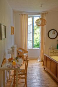 a living room with a table and chairs and a window at Maison Rives - Village du Livre de Montolieu in Montolieu