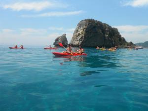 a group of people kayaking in the water near a rock at Pink Palace Beach Resort in Agios Gordios