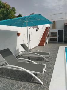 - un ensemble de chaises longues avec un parasol à côté de la piscine dans l'établissement Casa Daniela, à Tahiche