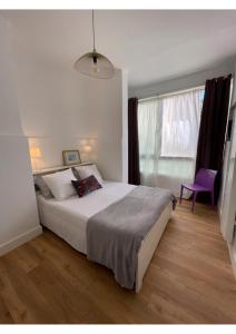 - une chambre avec un grand lit et une chaise violette dans l'établissement Appartement neuf, 2 chambres, climatisé, route des Sanguinaires, à Ajaccio
