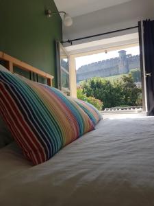 a bed with a colorful pillow in a room with a window at Maison vue Cité 2 in Carcassonne