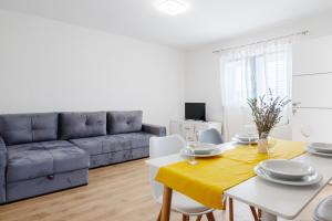 sala de estar con sofá, mesa y sillas en Apartmani Vuletić en Neum