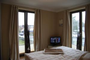 a bedroom with a bed and a tv and windows at Luxuswohnung Abendsonne in Wenningstedt