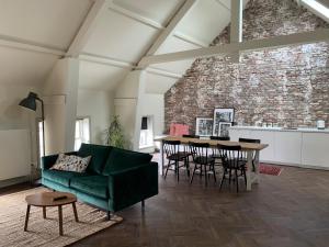 a living room with a green couch and a table at Hotel en restaurant Della Contessa in Buren