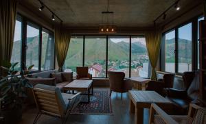 una stanza con divani, tavoli e finestre di Northgate Hotel Kazbegi a Kazbegi
