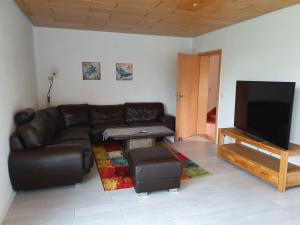 sala de estar con sofá de cuero y TV de pantalla plana en Ferienhaus Ursel in Otterndorf, en Otterndorf