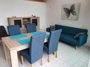 comedor con mesa y sofá azul en Ferienhaus Ursel in Otterndorf, en Otterndorf