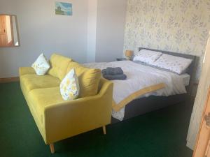 a bedroom with a yellow couch and a bed at Mussenden House in Articlave