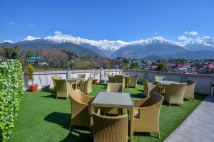 a patio with tables and chairs with mountains in the background at The Bliss Palampur in Pālampur