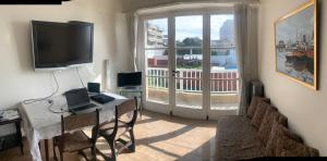 a living room with a television and a table with chairs at Mar del Plata frente al mar Biblioteca in Mar del Plata