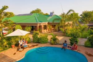 um grupo de pessoas sentadas em torno de uma piscina em frente a uma casa em Dzimbahwe Guest Lodge em Victoria Falls