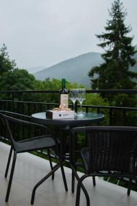 a table with a bottle of wine and glasses on a balcony at Likani Home in Borjomi