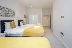 1 dormitorio con 2 camas con sábanas amarillas en Spacious 1 Bed Luxury St Albans Apartment - Free WiFi, en Saint Albans