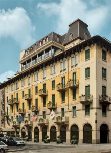 un grande edificio giallo con macchine parcheggiate di fronte di Andreola Central Hotel a Milano