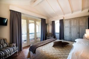 a bedroom with a bed and a chair and a window at Altarocca Wine Resort Adults Only in Orvieto