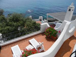 a balcony with white chairs and flowers and the ocean at Hotel Punta Rossa in San Felice Circeo