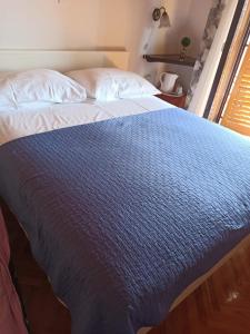 a bed with a blue blanket on top of it at Room Jelka 3 in Malinska