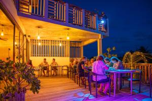 grupa ludzi siedzących w nocy przy stolikach na pokładzie w obiekcie Club Gabbiano w mieście Rasdhoo