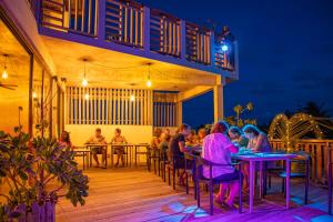 a group of people sitting at tables on a deck at night at Club Gabbiano in Rasdhoo