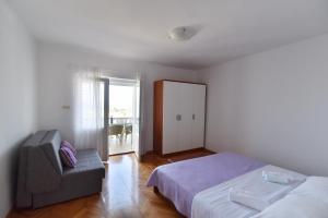 a bedroom with a bed and a chair and a window at Apartmani Badurina - Crnika in Lun