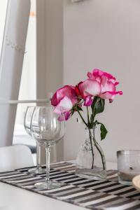 un vaso di vetro con fiori rosa e un bicchiere di vino di SEA- ROOM-E a Ladispoli