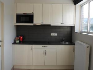 eine Küche mit weißen Schränken, einer Spüle und einer Mikrowelle in der Unterkunft B&B Caramel in Turnhout