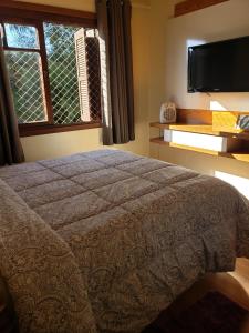 a bedroom with a bed and a tv and a window at Apartamento Flor de Canela in Canela