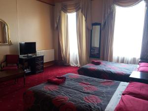 ein Hotelzimmer mit zwei Betten und einem Fernseher in der Unterkunft Bellevue Guest House in Edinburgh + 20 Fotos