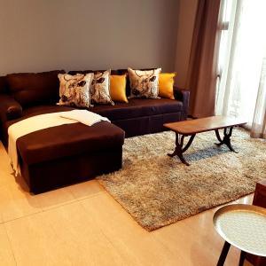 a living room with a brown couch and a table at Pearls of Umhlanga in Durban