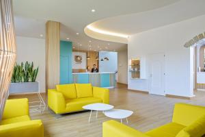 a waiting room with yellow chairs and a table at Lu' Hotel Porto Pino in SantʼAnna Arresi