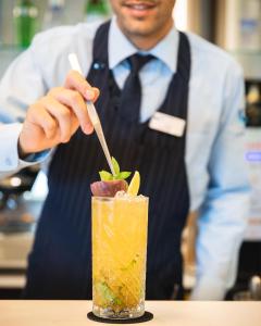 a man in a tie is stirring a drink at Lu' Hotel Porto Pino in SantʼAnna Arresi