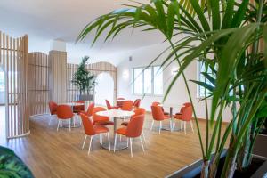 a room with tables and chairs and a potted plant at Lu' Hotel Porto Pino in SantʼAnna Arresi
