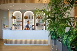 a man standing at a counter in a restaurant with plants at Lu' Hotel Porto Pino in SantʼAnna Arresi