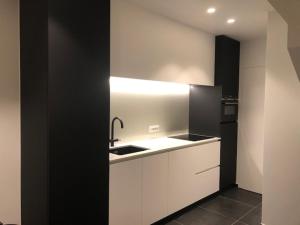 een keuken met een wastafel en een zwarte koelkast bij bloc79/zero in Knokke-Heist