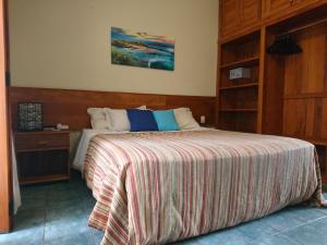 1 dormitorio con 1 cama grande con manta a rayas en Galápagos ApartHotel, en Ilhabela