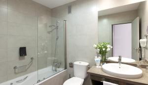
a bathroom with a tub, toilet, sink and mirror at Vértice Sevilla Aljarafe in Bormujos
